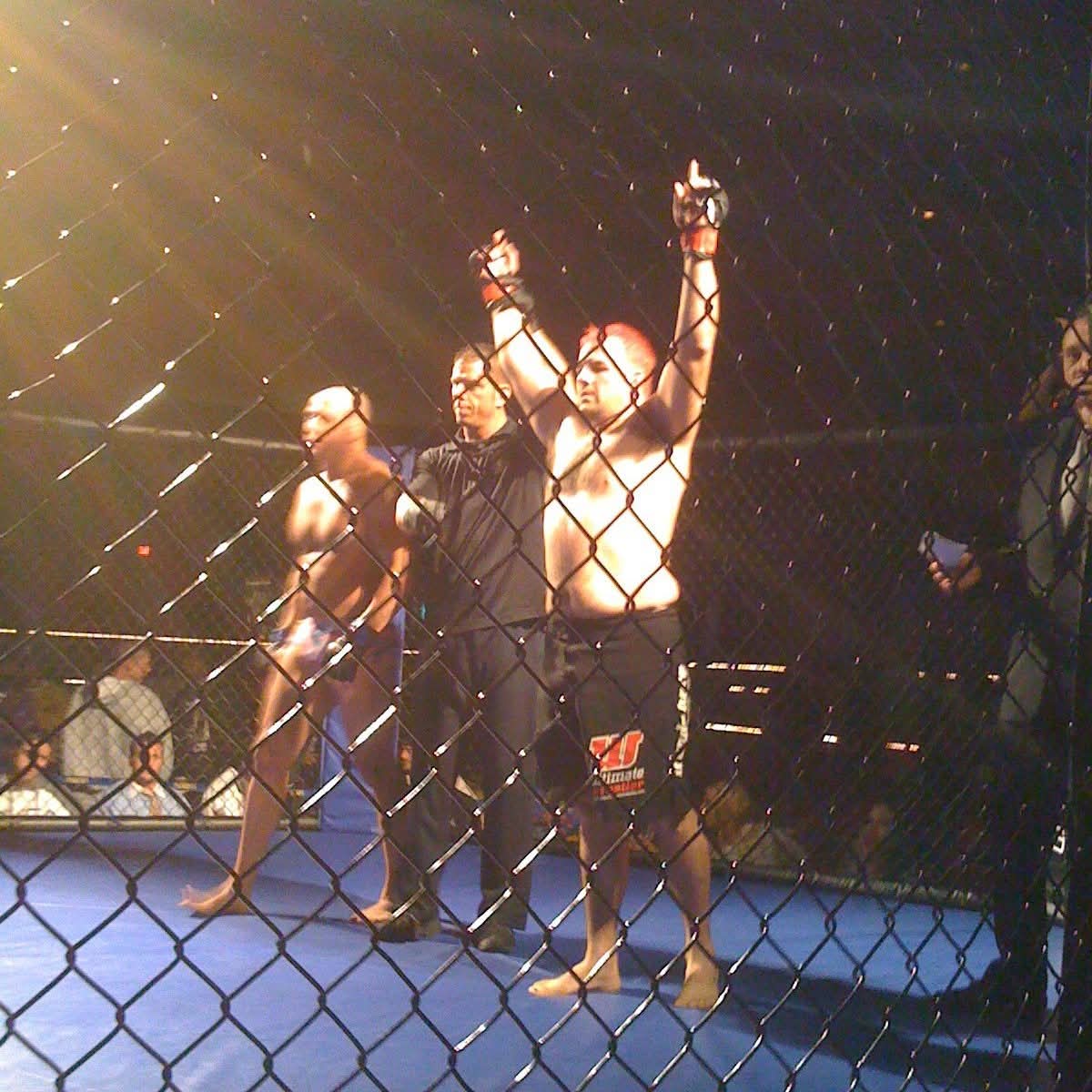 Ruffhouse student holding hands up in victory at MMA match.