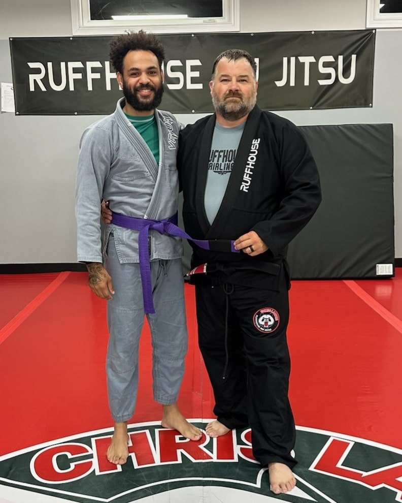 Ruffhouse Jiu-Jitsu student smiling with instructor wearing gi uniforms.