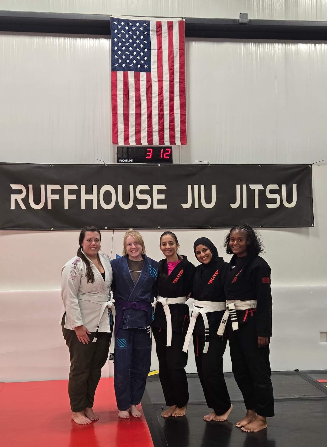 Ruffhouse Jiu-Jitstu women students smiling on mats wearing gi uniforms.